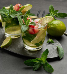 Refreshing mojito cocktail with lime, mint, strawberry, and ice on dark background