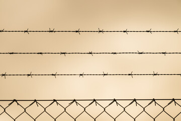 Barbed wire fence silhouette against grey sky.