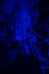 Thick curling blue smoke in dark environment.