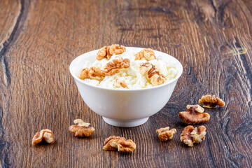 Fresh cottage cheese with walnuts in a white bowl.