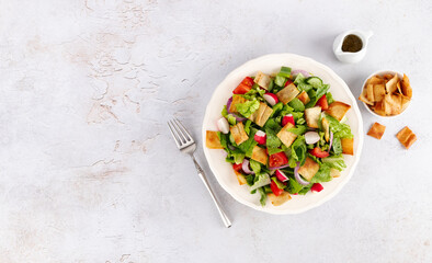 Lebanese fattoush salad with romaine, fresh vegetables and fried pita pieces on white background. Top view. Copy space.