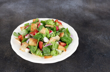 Lebanese bread salad with fresh vegetables and pita on a gray background.