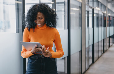 Smiling female professional using tablet in modern office hallway. Confident and engaged, Female...