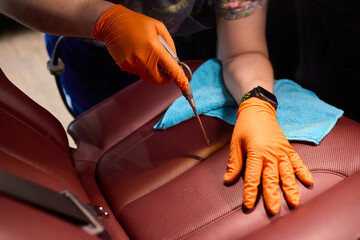Cleaning a Luxury Car Seat with a Detail Brush and Foam for Maintaining Its Appearance