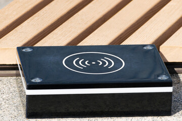 a device for wireless charging of electronic gadgets is installed near a bench in a city park