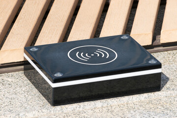 a device for wireless charging of electronic gadgets is installed near a bench in a city park