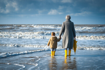Grandmother and grandson at water's edge North Sea back view