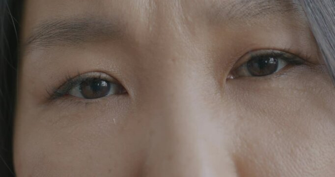 Close-up slow motion portrait of sad Asian woman's eyes looking at camera feeling troubled and worried. Face expression and negative emotion concept.