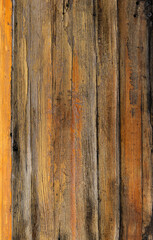 Obraz premium A closeup of the aged weathered wooden side of a boat with worn textures and painted yellow and orange planks. 