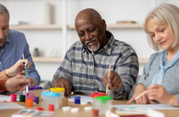 Art therapy for seniors concept. Happy multiracial elderly men and women enjoying painting with...