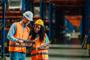 Warehouse workers using digital tablet and clipboard for inventory management