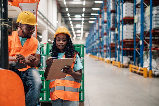 Warehouse workers discussing logistics using clipboard and forklift