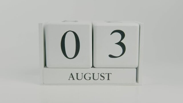 A hand flips a wooden calendar from August 3rd to August 4th on a white background, marking the transition to a new day