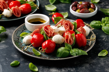 Mini skewer appetizers with salami, mozzarella and tomatoes. Healthy antipasto skewer.