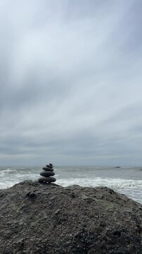 A rock cairn sits on a large boulder at Ruby Beach with ocean waves