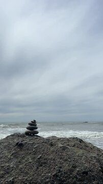 A rock cairn sits on a large boulder at Ruby Beach with ocean waves