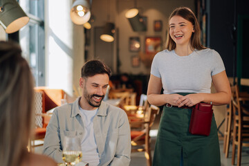 Waitress taking order from happy customers in restaurant