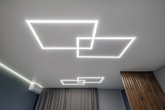 suspended ceiling with halogen spots lamps in form of squares and rectangles and drywall construction in empty room in apartment or house. Stretch ceiling white and complex shape.