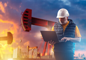 Portrait man oil worker. Petroleum pumps behind specialist with laptop. Man oil worker uses computer while standing in field. Extraction and processing of petroleum. Fuel industry employee at sunset