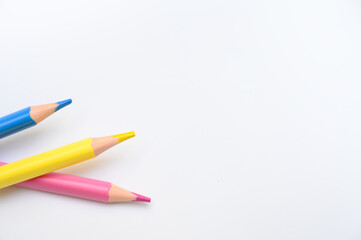 Three vibrant pencils lie on a clean white surface, symbolizing creativity, education, and...