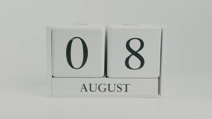 A hand flips a wooden calendar from August 8th to August 9th on a white background, marking the shift to a new day