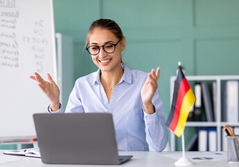 E-learning with teacher, social distancing, new normal. Happy female tutor giving German language...
