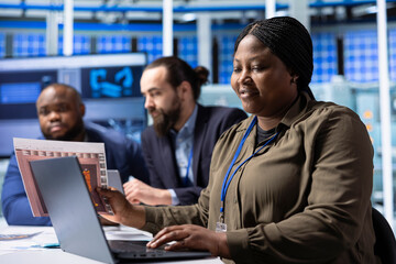 Industrial plant researchers using notebook for research and development data analysis. Factory engineering team members working together to research innovative photovoltaic materials using laptop