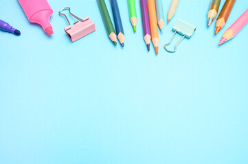 Flat lay of school stationery like pencils, clips, and sharpeners on blue background. Ideal for educational content, back to school promotions, and academic materials.