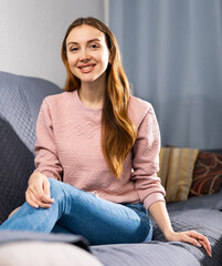 Portrait of a smiling confident young woman sitting on a sofa in a room