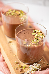 Two glasses of chocolate mousse topped with chopped pistachios