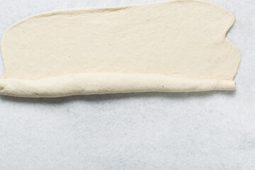Overhead view of baozi dough being shaped on a white granite countertop, top view of mantou dough being divided on granite countertop, process of making bao bun