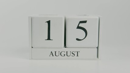 A hand flips a wooden calendar from August 15th to August 16th on a white background, marking the steady movement of time through the month