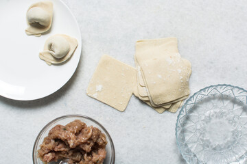 Overhead view of dumpling being wrapped, top view of wonton being filled, process of making homemade wontons