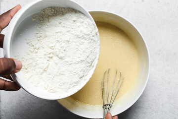 Overhead view of flour being mixed into cake batter, top view of vanilla cake batter being mixed, process of making vanilla cake
