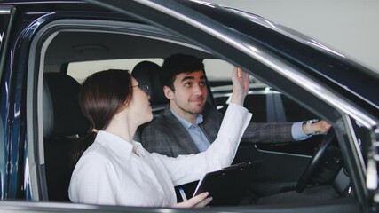 Sales professional discusses vehicle options with customer inside modern car dealership during afternoon hours