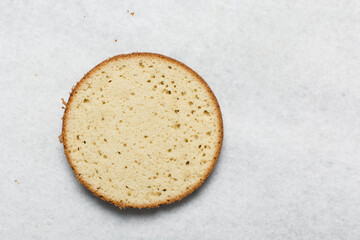 Overhead view of vanilla cake layers on a white countertop, top view of vanilla cake slices about to be assembled, process of making layered cake