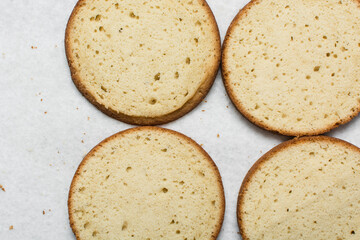 Overhead view of vanilla cake layers on a white countertop, top view of vanilla cake slices about to be assembled, process of making layered cake