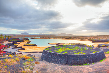 Lago de la Santa in Lanzarote features volcanic rock formations and calm saltwater pools under a...