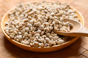 Dried Job's tears or adlay millet seeds in wooden bowl with spoon, Food ingredient
