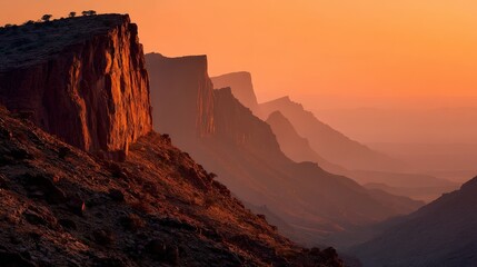 Silhouette of a canyon wall against an orange sunset sky, capturing the beauty of nature at dusk.