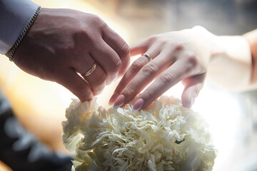 Couple exchanging wedding rings while holding a bouquet during their registration ceremony