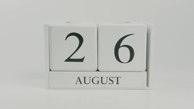 A hand flips a wooden calendar from August 26th to August 27th on a white background, marking the transition to the next day