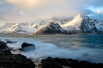 Sunrise at Vareid beach with snow-covered mountains, Flakstadpollen fjord, Lofoten, Norway
