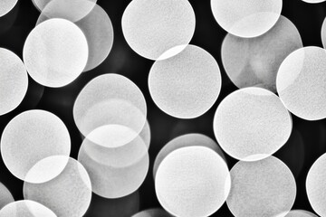 Abstract blurred bokeh circles with white glowing light on black background. Minimal pattern for modern soft design, texture, or wallpaper concept.