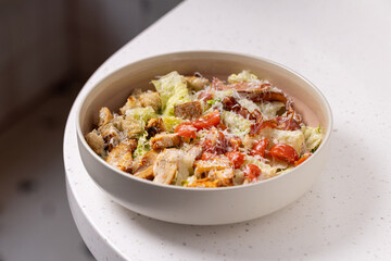 
Caesar Salad with Grilled Chicken, Parmesan and Croutons.
Classic Caesar salad featuring grilled chicken pieces, cherry tomatoes, croutons and grated Parmesan in a neutral bowl.