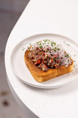 Beef Tartare Toast with Pickled Onions and Chives.
Open-faced sandwich topped with finely chopped beef tartare, pickled red onion and fresh chives on toasted bread.