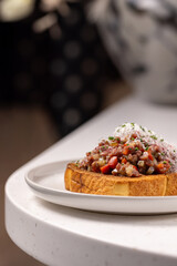 Beef Tartare Toast with Pickled Onions and Chives.
Open-faced sandwich topped with finely chopped beef tartare, pickled red onion and fresh chives on toasted bread.