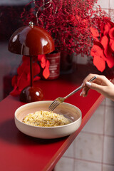 Creamy Pistachio Dessert Pasta.
Spaghetti in a smooth sweet cream sauce, topped with crushed pistachios, served in a ceramic bowl on a red background with floral decor.