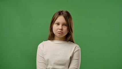 Fototapeta premium Teenage girl posing at camera with sad upset pouting face, negative expression, isolated on chroma key green screen studio background mockup.