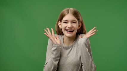 Teenage girl posing at camera holding hands, wow surprise, smiling positive expression, isolated on chroma key green screen studio background mockup.